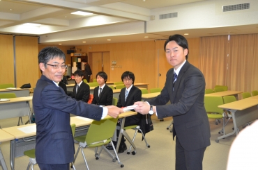 学生に助成金を手渡す松井会長㊧=豊橋技術科学大学で