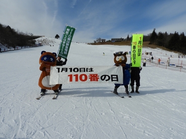 横断幕を掲げて滑走したポンタ(左)とコノハ警部=茶臼山高原スキー場(6日、設楽署提供)