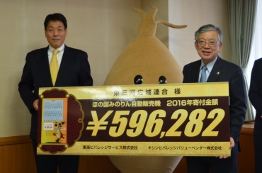 寄付金が記されたボードを手にする斉吉社長㊧と佐原市長=豊橋市役所で