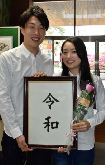 「令和」の額とバラを手に入籍した竹下さん夫妻=豊川市役所で