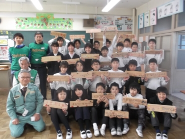 木の板を手に笑顔の児童と伊藤会長㊧(イトコー提供)