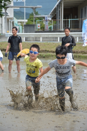 全身を泥だらけにしながら田んぼで遊ぶ児童たち=賀茂小学校近くの田んぼで