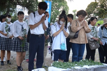 追悼碑の前に献花、手を合わせる参加者=湊町公園で