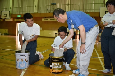 管財の社員㊨からモップの絞り方を教わる生徒ら=豊川特別支援学校で
