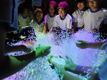 ボールを的に当てると光の粒が舞い上がる「Splash Display」を楽しむ児童たち=豊橋市美術博物館で