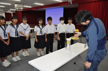 オレンジジュースを透明にする実験を見守る生徒たち=三菱ケミカル愛知事業所で