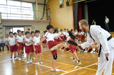 選手が手にする防具に蹴り、テコンドーを体験する児童たち=吉田方小学校で