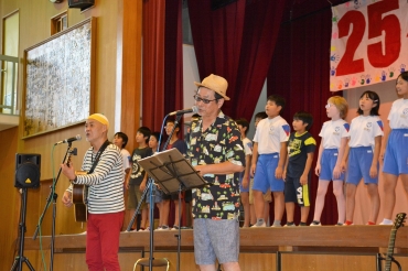 児童たちと校歌を合唱する富安さん㊧と金藤さん=つつじが丘小学校で