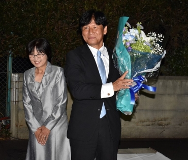 花束を贈られ、笑顔の竹本氏㊨と妻の利恵子さん=豊川市桜木通の選挙事務所で
