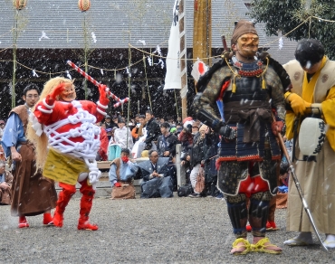 大粒の雪が降る中で行われた「赤鬼と天狗のからかい」=安久美神戸神明社で