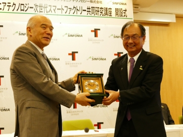 武藤会長㊨から記念品の時計を受け取り、「共同研究の証しとして長く使わせていただく」と話す大西学長=豊橋技科大で