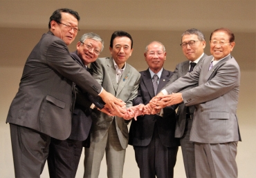 防災面での連携強化を確認し、手を合わせる三遠南信の首長、経済界代表ら=長野県飯田市の鼎文化ホールで