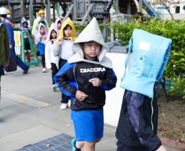 防災頭巾を被って瓜郷遺跡まで避難する児童ら=津田小学校で