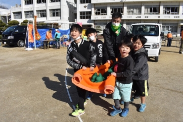担架の搬送トライアルに挑戦する子どもたち=長沢小学校で