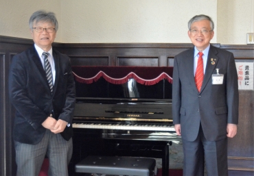 贈った国産ピアノと笑顔の藤原さん㊧、佐原市長=豊橋市公会堂で