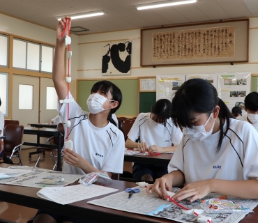 厄払いや縁起物を連ねた「つるし飾り」をつくる生徒たち=田原市の福江中学校で