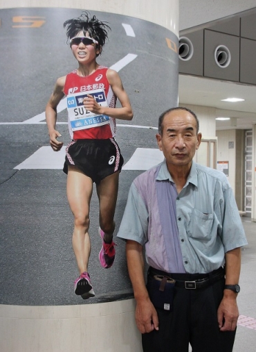 豊橋市役所で展示しているMGCを走る鈴木選手の作品と津坂さん