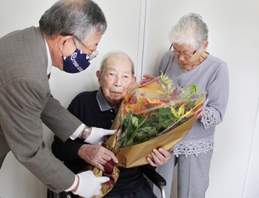 花束を受ける片山信男さんと、よね子さん=豊橋市中原町で