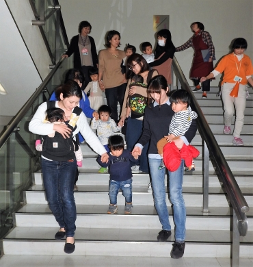 子どもを抱いたり、手をつなぎながら慎重に階段を降りる避難訓練の参加者ら=プリオで