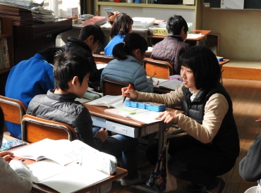 子どもの目線で机間指導を行う石田さん㊨=桜町小学校で