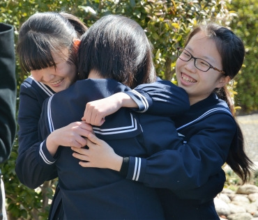 抱き合いながら喜びを分かち合う女子生徒ら=時習館高校で