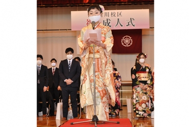 新成人を代表しマスク姿で誓いの言葉を述べる女性=豊橋市立新川小学校で