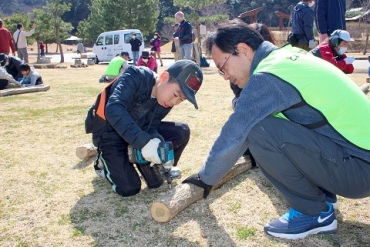とよかわ里山の会メンバーとシイタケの菌打ち体験をする男子児童=東三河ふるさと公園で(2018年3月)