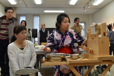 座繰りを体験する女工役の若者(右)と指導する矢澤さん。左後方は伊沢さん=豊橋市大井町で