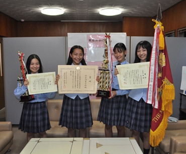 優勝旗などを持つ田中さん、澤村さん、杉田さん、福士さん(左から)=東愛知新聞社で