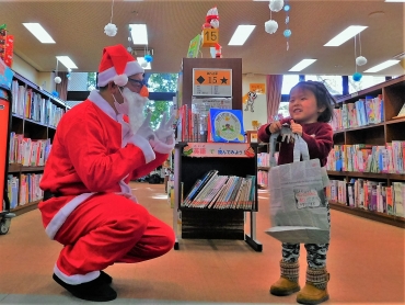 サンタ姿の斎藤館長がラッピングブックをプレゼント=豊橋市中央図書館で