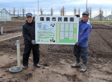市民農園の看板を手にする丸山さん親子=豊川市篠束町で