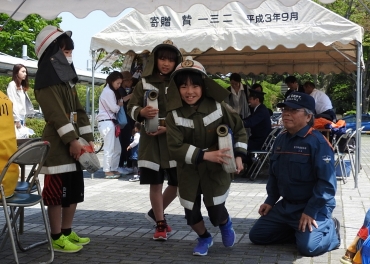 消防チャンレジで消火ホースを抱えて走る女の子たち=豊川市総合体育館前で