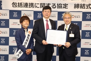 浅井市長と協定書を交わす泉社長(中央)。左は小鈴木さん=豊橋市役所で