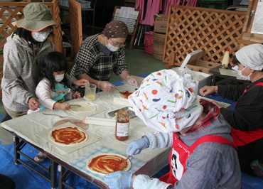 ピザ作りをする親子とスタッフ
