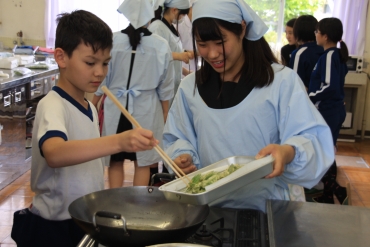高校生と一緒に茶葉の天ぷらを揚げる児童=県立新城高校で