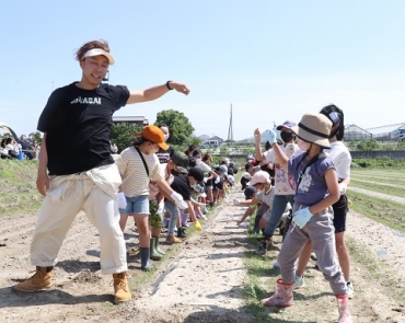 「チューチュートレイン」のダンスで枝豆の種をまくUSAさん(左手前)と子どもたち=東七根町で