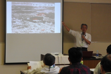 工廠建設前の豊川市の航空写真で説明する平松さん=桜ヶ丘ミュージアムで