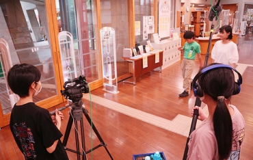図書館に閉じ込められたシーン。カメラと音声(手前)も子どもたちが担った=田原市中央図書館で
