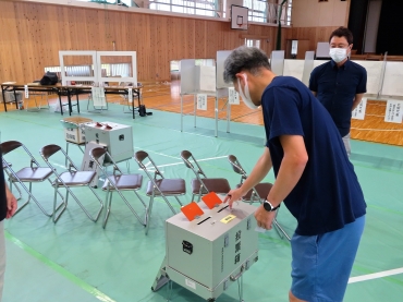 最初の1票を投じる男性=豊橋市立吉田方小学校で